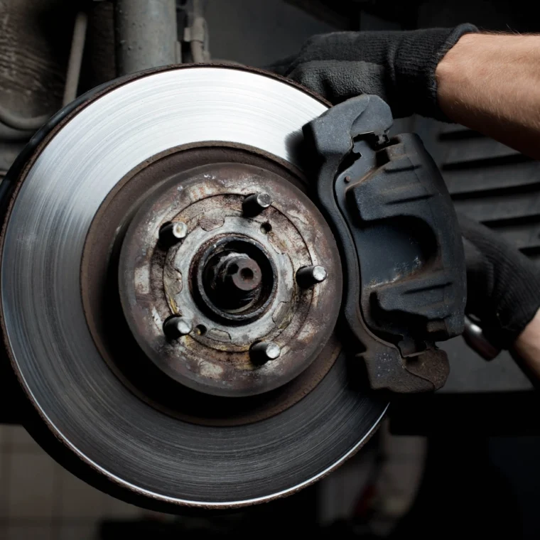 Closeup of car mechanic repairing brake pads and rotors.