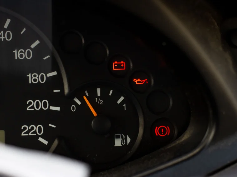 Car dashboard with speedometer, fuel gauge at half, and three warning lights illuminated: battery (highlighting the need for Battery Services), oil, and brake.