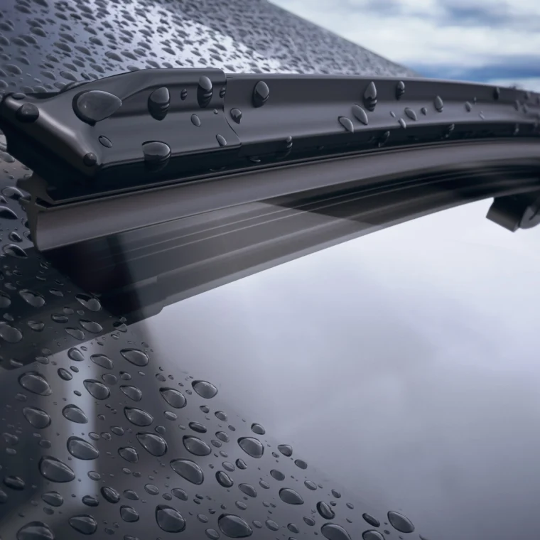 A closeup of a car's windshield and wiper blade with rain drops