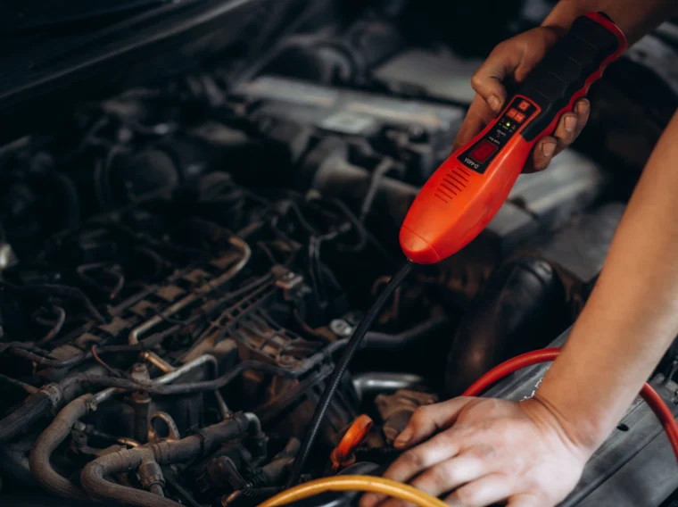 A technician checking a car's air conditioning system or performing a refrigerant recharge as part of air conditioning services at Grease Monkey.