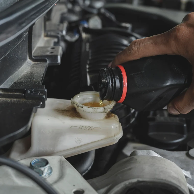 Auto mechanic topping off fluid in a reservoir.