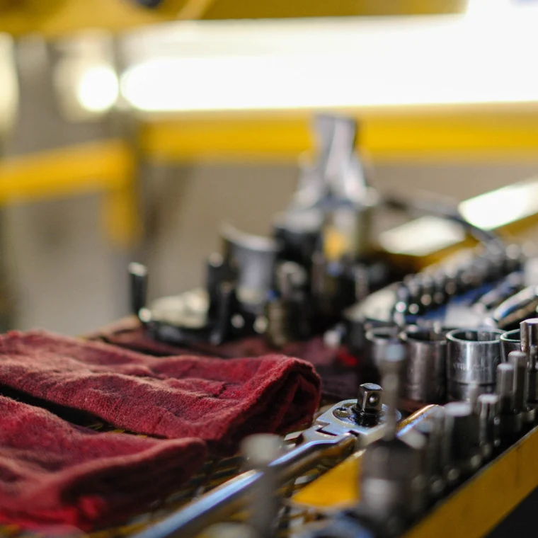 A workbench with red cloths, various wrenches, and sockets neatly arranged, with tools and machinery parts in the background—ideal for air conditioning services or AC repairs.
