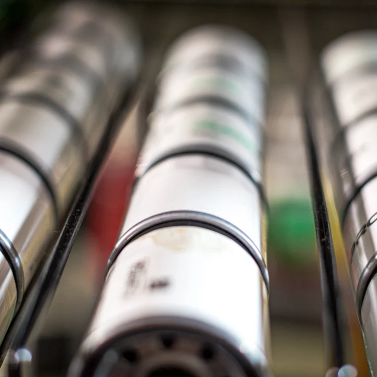 Close-up view of cylindrical oil filters arranged in parallel rows on a metal rack.
