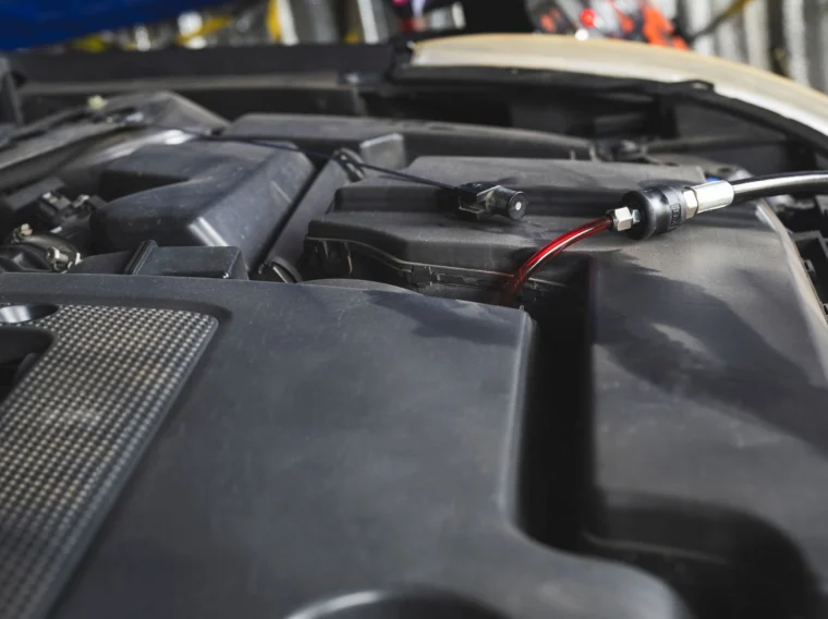 A car engine with an oil extraction tool inserted, pulling out dark red engine oil during a maintenance procedure—demonstrating the effectiveness of professional Fluid Exchange Services.