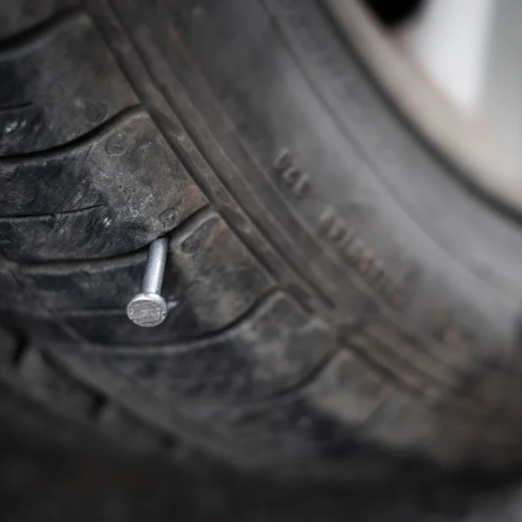 Close up of a metal nail sticking out of a tire.