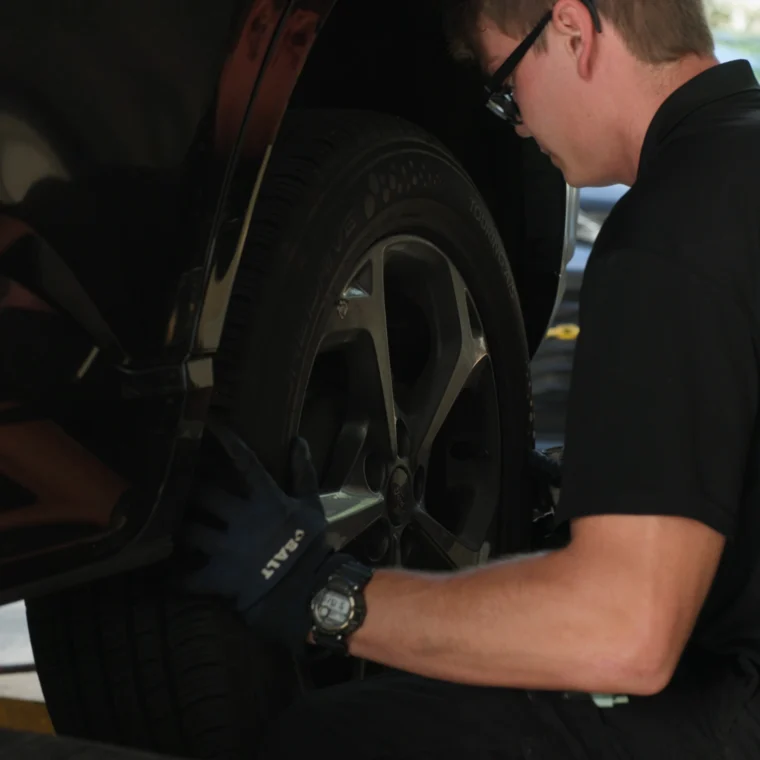 A technician rotating the tire of a vehicle.