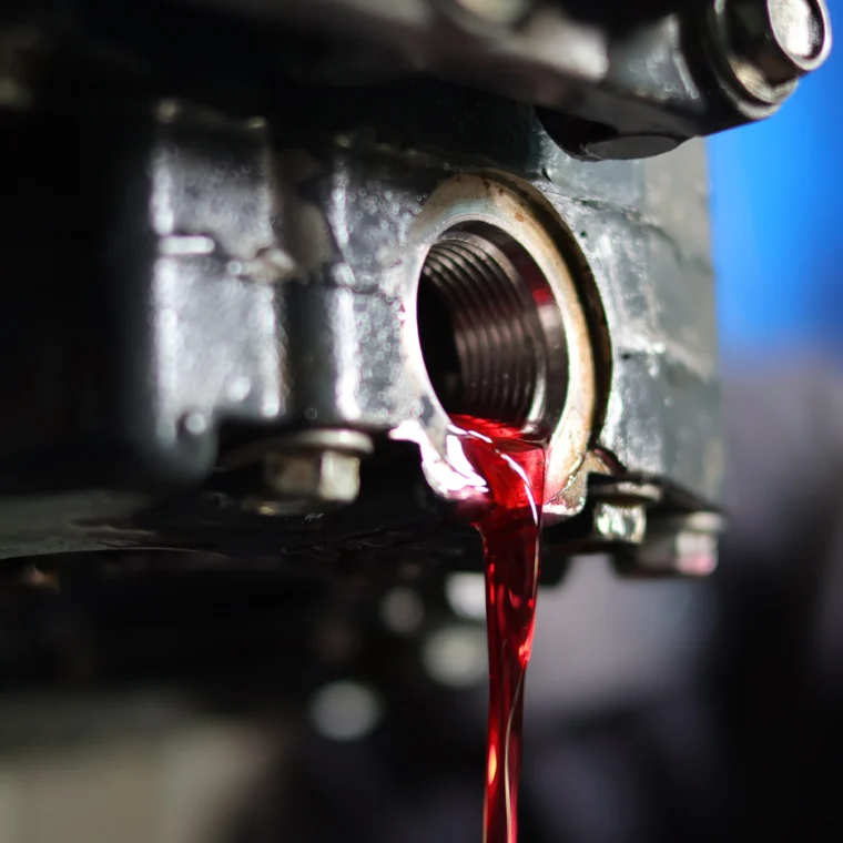 Open drain plug with fluid pouring out.