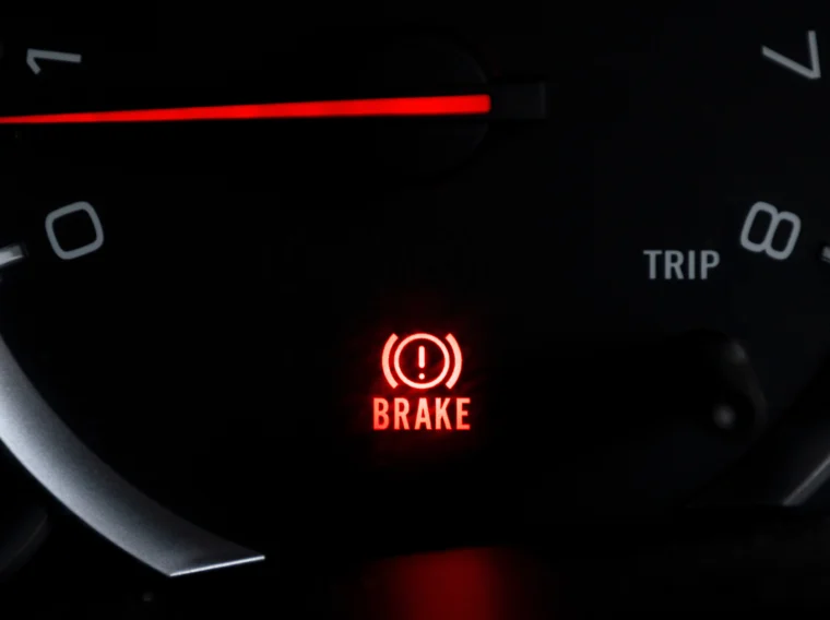 Car dashboard light showing BRAKE icon lit up.