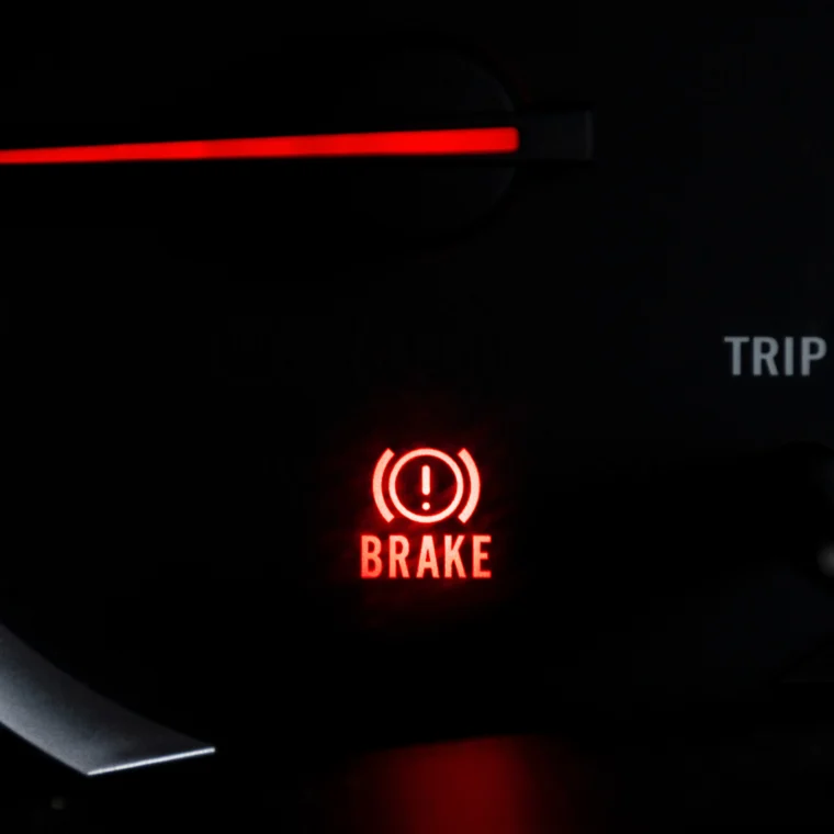 Car dashboard light showing BRAKE icon lit up.