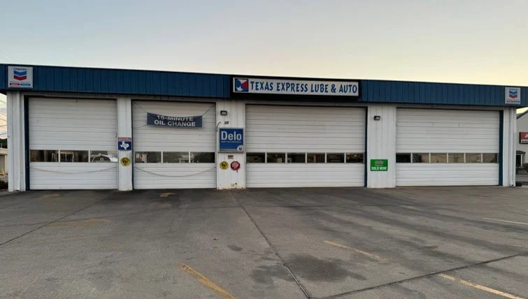 Exterior of Texas Express Lube & Auto, a service garage with four closed bays, a Chevron Texaco sign, and visible parking spaces in front.