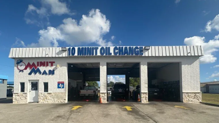 Exterior of an auto service building with three garage bays labeled "10 MINIT OIL CHANGE" and "MINIT MAN" signage on the front wall.
