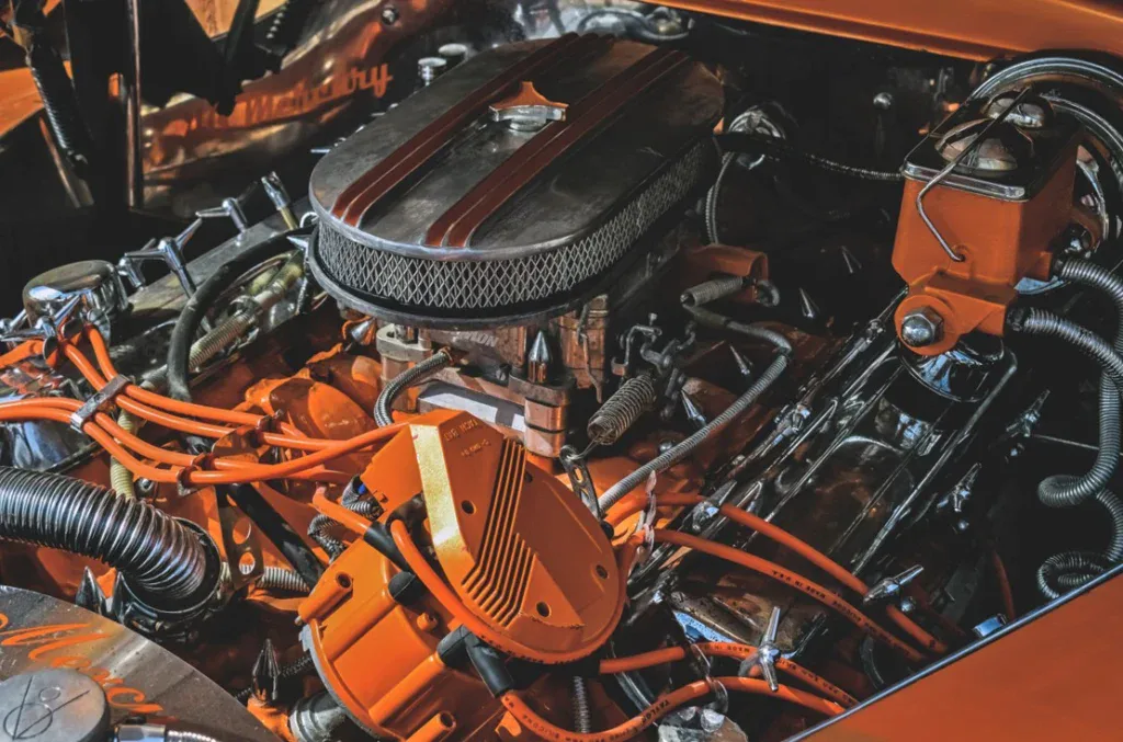 Close-up view of a car engine with chrome and orange components, visible air filter, wires, hoses, and metal detailing—reminding you to save your engine with regular oil changes in Pocatello Idaho.