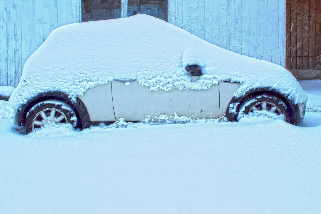 A car parked in front of a building in Jerome, Idaho, is mostly covered in snow after a heavy snowfall—ready for a Grease Monkey checkup to ensure engine long life once the weather clears.