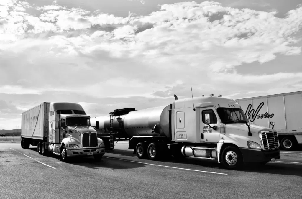 Two large semi-trucks are parked side by side in a parking lot under a partly cloudy sky, ready for an engine saving quick oil change in Pocatello.