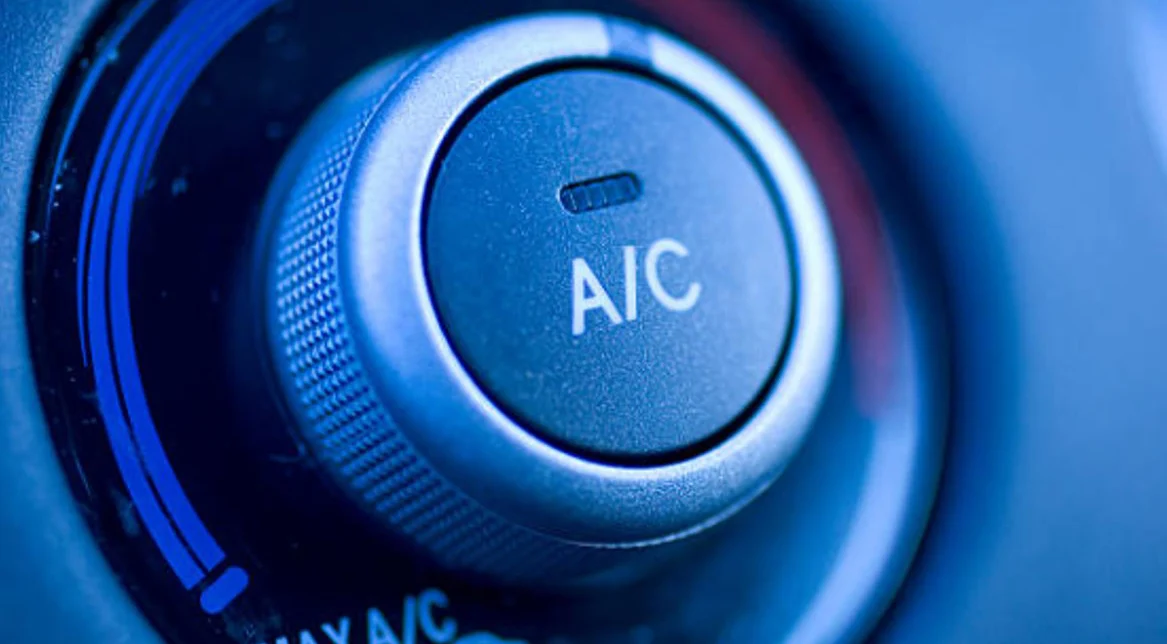 Close-up of a car air conditioning control knob showing the "A/C" label and surrounding temperature adjustment dial.