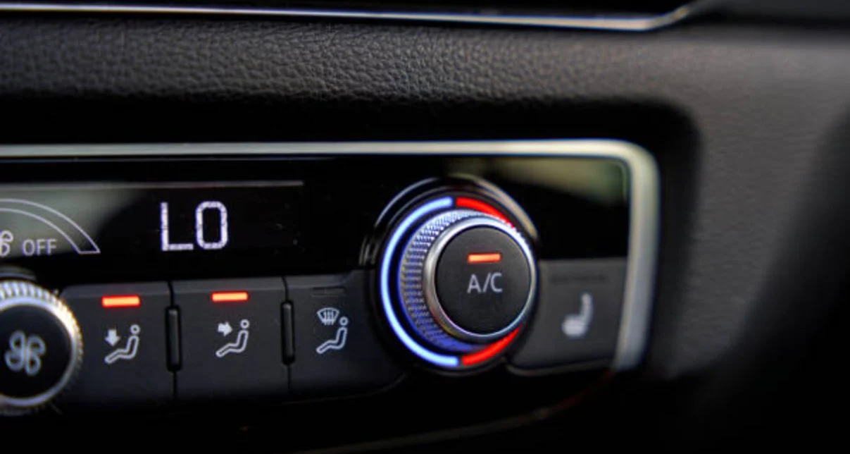 Close-up of a car climate control panel showing the A/C button activated, temperature set to "LO," and seat heating button visible on the right.