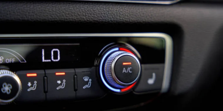 Close-up of a car climate control panel showing the A/C button activated, temperature set to "LO," and seat heating button visible on the right.
