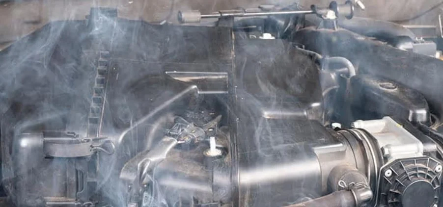 A car engine with visible smoke rising from it in Idaho Falls, indicating possible overheating or the need for an oil change or other mechanical issues.
