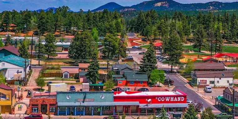 A small town with colorful buildings, trees, and mountains in the background; the main street features a red-and-white store called Cowhand.