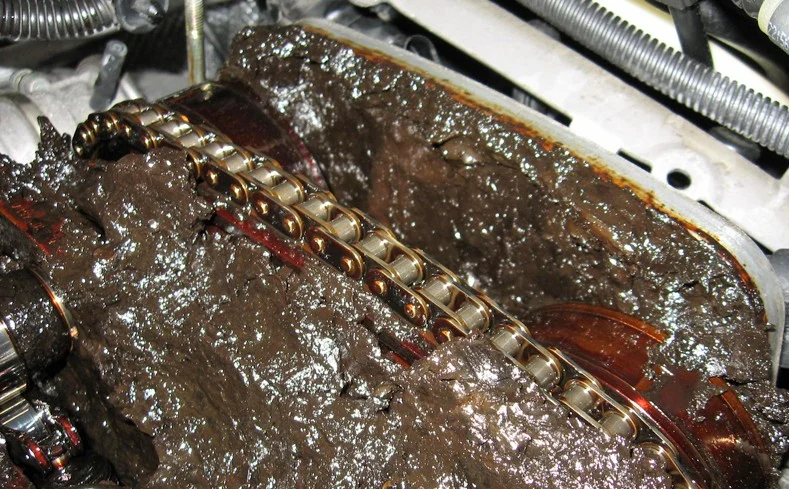 Close-up of an engine component covered in thick, black sludge, highlighting severe oil sludge buildup—an issue that regular engine maintenance or timely oil change can help prevent, especially for Idaho Falls engines.