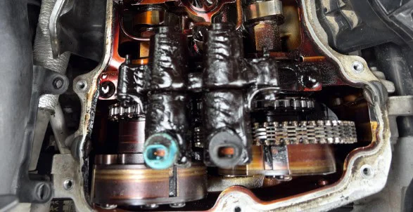Close-up view of a Laramie engine’s internal components with visible sludge buildup and oil residue on metal parts, highlighting the importance of regular oil change and proper engine maintenance.