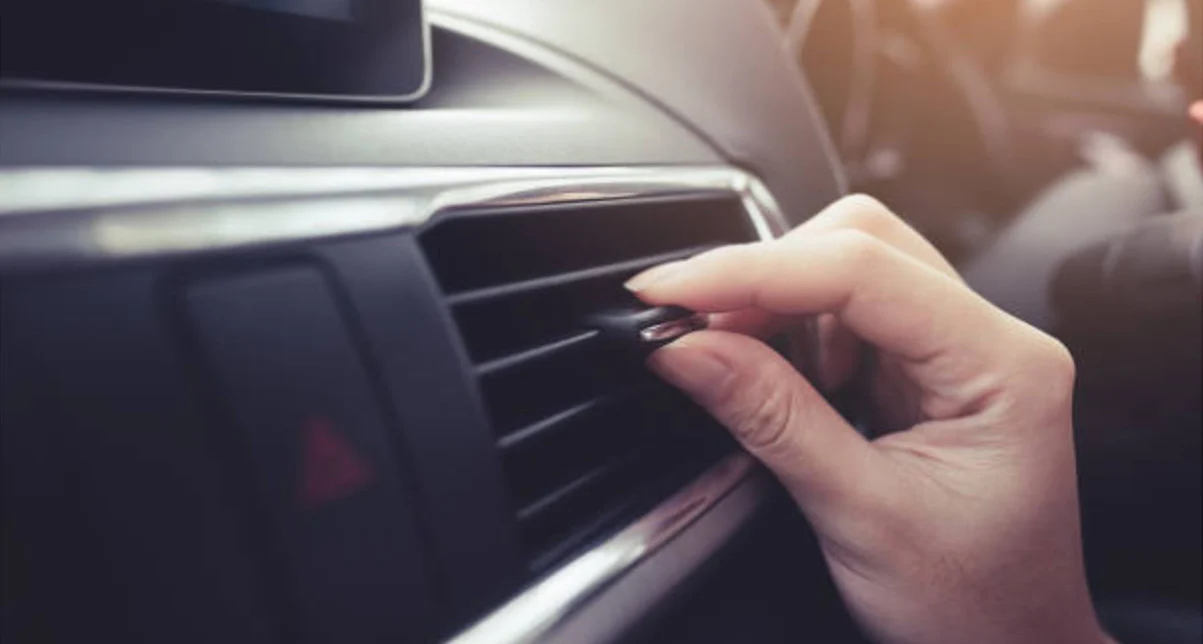 A person adjusts the air vent on a car dashboard, ensuring optimal Chevy AC care for comfortable drives around Magic Valley.