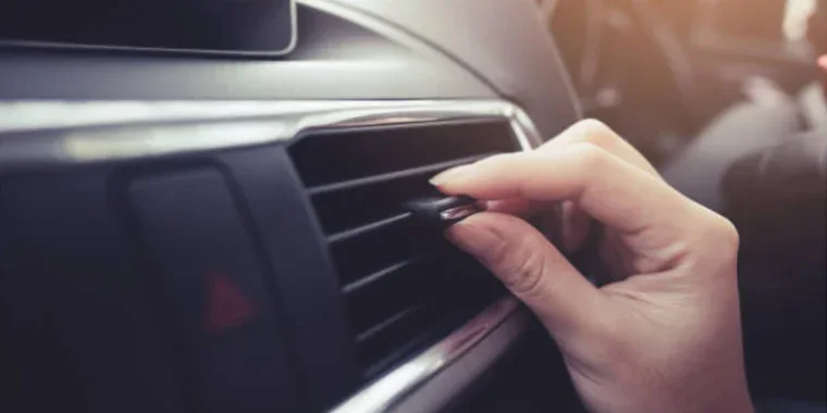 A person adjusts the air vent on a car dashboard, ensuring optimal Chevy AC care for comfortable drives around Magic Valley.