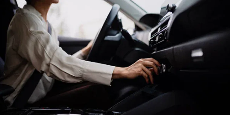 Jerome sits in the driver’s seat of his car, smiling as he reaches forward to adjust the dashboard controls, showing off his vehicle AC care after a visit to Grease Monkey.