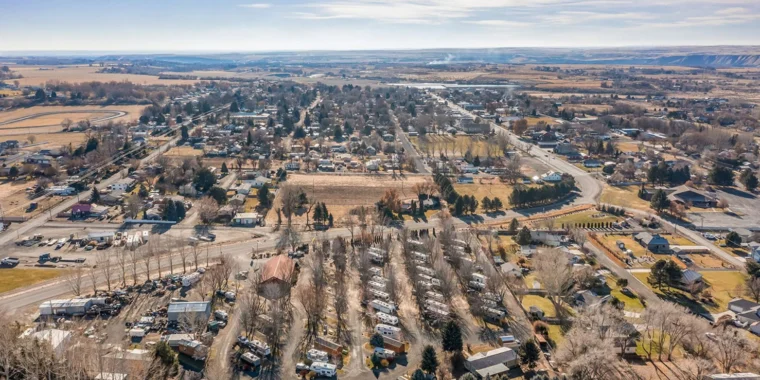 Aerial view of a small rural town with scattered houses, RVs, leafless trees, and wide open fields under a clear blue sky—perfect scenery for understanding the importance of vehicle maintenance in Jerome Idaho.