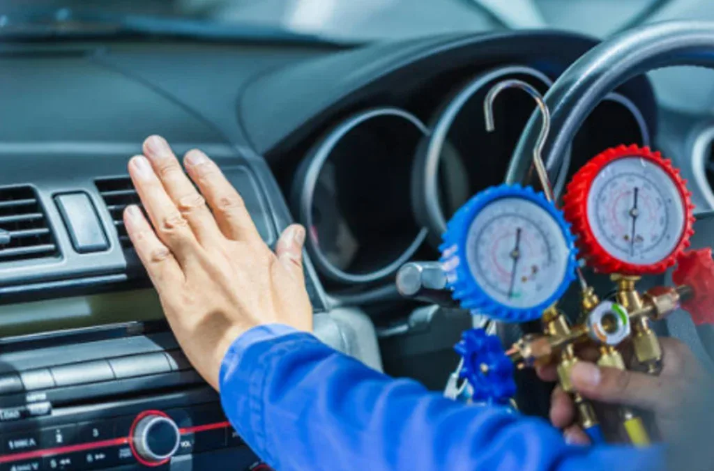 A technician delivers Expert AC Care by checking a Chevy’s air conditioning system with a manifold gauge while placing a hand near the air vent inside the vehicle.