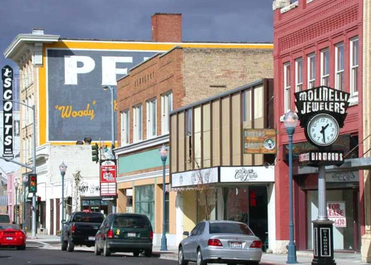 Downtown street with parked cars, historic brick buildings, business signs, and a vintage clock outside Molinelli Jewelers under a cloudy sky—drivers from Southeast Pocatello can also spot local shops offering vehicle air conditioning service.