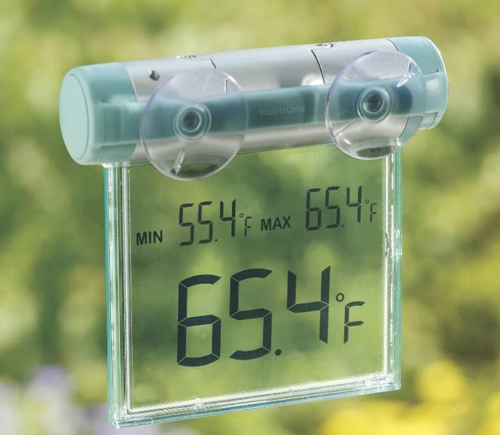 Digital thermometer attached to a window with suction cups in Twin Falls, Idaho, displays a temperature of 65.4°F, showing minimum and maximum readings of 55.4°F and 65.4°F—ideal info for vehicle air conditioning checks.