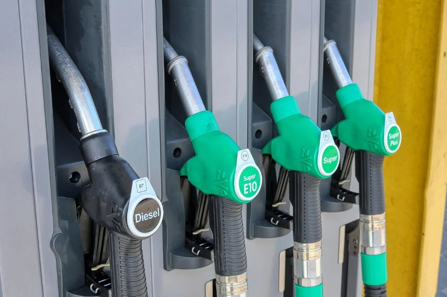 Four fuel pump nozzles at a Laramie Wyoming gas station, labeled Diesel, Super E10, Super, and Super Plus, attached to their dispensers—perfect for topping off before servicing your vehicle air conditioning.