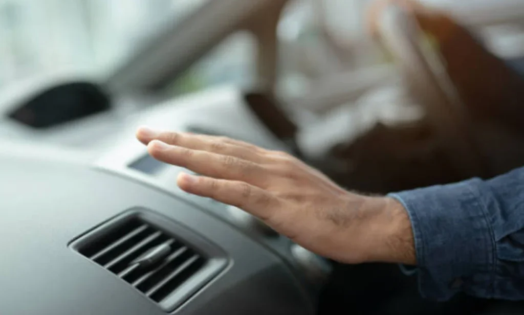 A person’s hand hovers over a car’s air conditioning vent inside a vehicle in Aurora, Colorado.