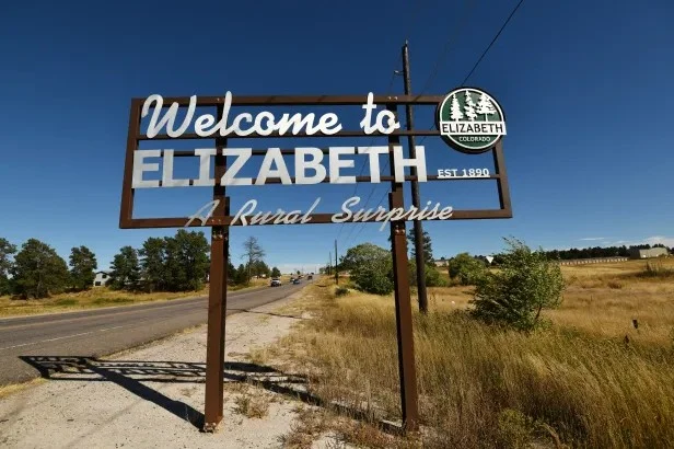 A roadside sign reads "Welcome to ELIZABETH, COLORADO. EST. 1890. A Rural Surprise," with trees and open fields in the background—a fitting sight before stopping for Elizabeth Colorado vehicle air conditioning service nearby.