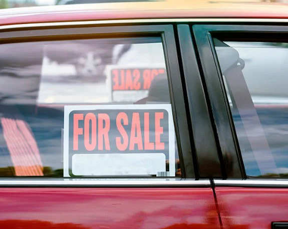 A "For Sale" sign is displayed on the rear window of a red car in Jerome, Idaho, highlighting its reliable vehicle air conditioning.