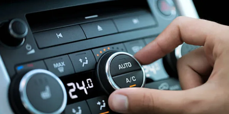 A hand adjusts the automatic climate control knob on a car dashboard, displaying a temperature setting of 24°C.