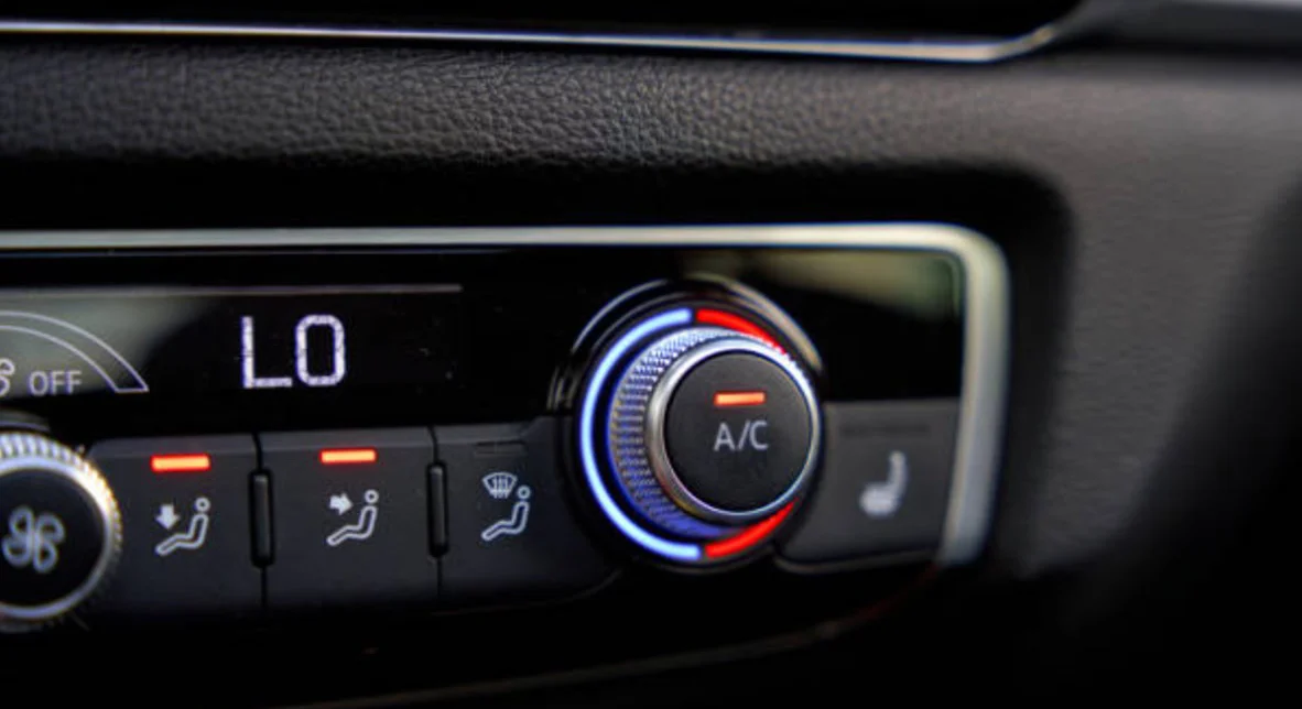 Close-up of a car climate control panel set to low temperature, with the A/C button illuminated and seat heating indicator visible.