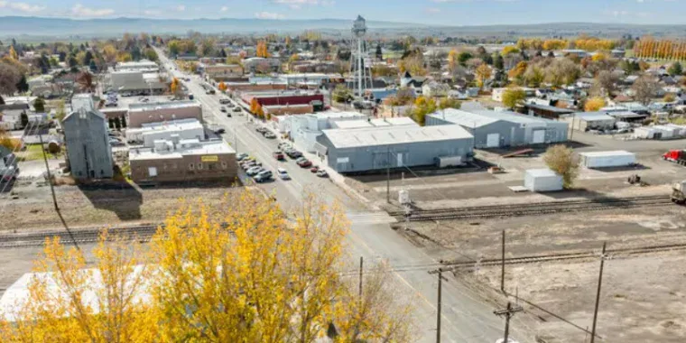 Aerial view of Kimberly, Idaho in Magic Valley with a water tower, main street, railroad tracks, and autumn trees under a partly cloudy sky—perfect for spotting local Vehicle Air Conditioning Service shops.