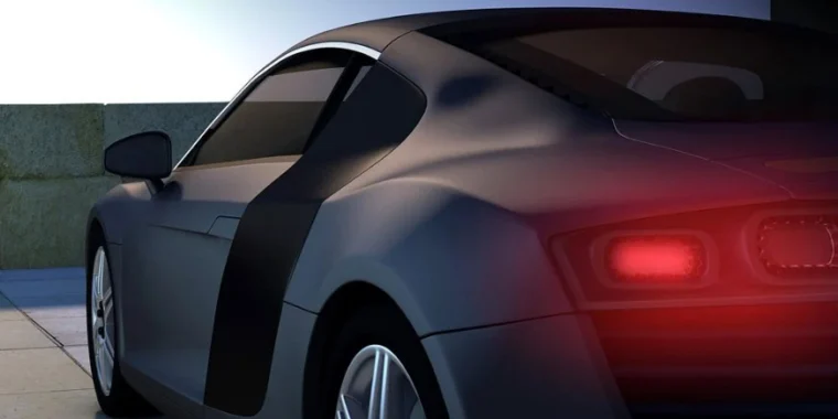 A sleek black sports car with its brake lights illuminated is parked outdoors on a tiled surface near a low wall at dusk, highlighting the importance of regular brake system repair and vehicle maintenance—services expertly provided by Grease Monkey Rexburg.