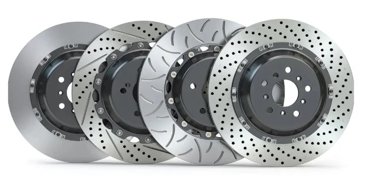 Four different types of car brake discs, including solid, slotted, drilled, and drilled-slotted designs—essential components of any reliable brake system—are arranged side by side on a white background. Perfect for anyone in Jerome Idaho seeking quality vehicle service or upgrades.