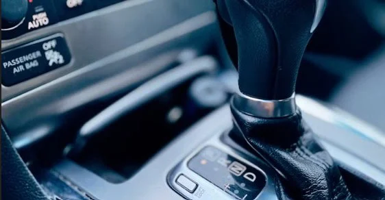 Close-up of a Laramie’s automatic gear shift and center console, showing part of the dashboard and control buttons—an essential focus point for drivers to spot any transmission warning signs.