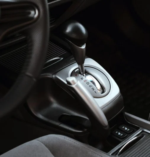 Close-up of a car’s automatic transmission gear shift lever with positions labeled P, R, N, D, and L, located on the center console next to the driver’s seat—a common sight for drivers navigating the Yellowstone Highway Corridor near Rexburg.
