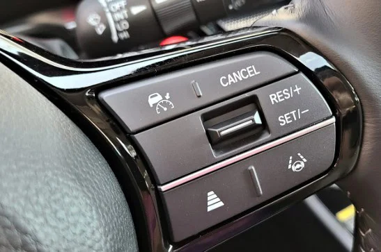 Close-up of a car steering wheel showing cruise control buttons, including cancel, resume/accel, set/decel, lane keep assist, and distance adjustment—a helpful view for Laramie drivers who want to stay focused on the road and spot transmission warning signs before transmission problems arise.