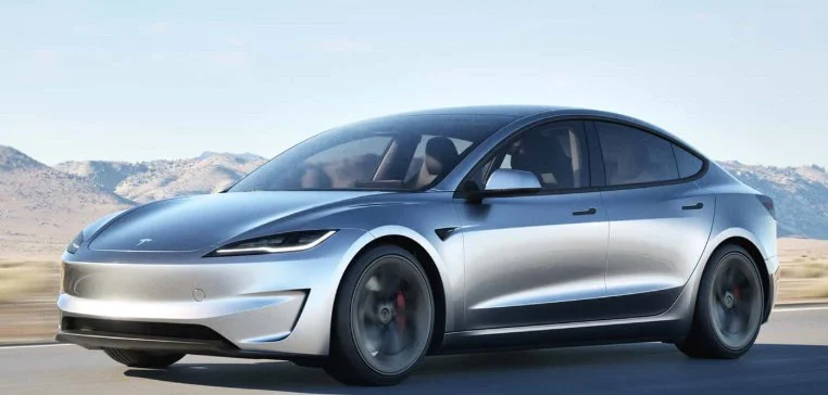 A silver electric sedan drives on I-225 in Aurora, Colorado, with mountains and a clear sky in the background, prepared for any transmission emergency along the way.