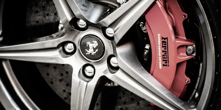 Close-up of a Ferrari wheel showing a five-spoke alloy rim, carbon ceramic brake disc, and red brake caliper with the Ferrari logo—an excellent reminder of the importance of regular brake inspection and professional brake service, whether you drive in Littleton, Colorado or anywhere else.