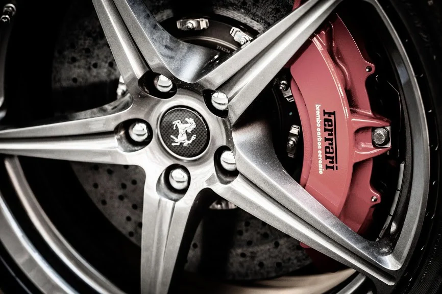 Close-up of a Ferrari wheel showing a five-spoke alloy rim, carbon ceramic brake disc, and red brake caliper with the Ferrari logo—an excellent reminder of the importance of regular brake inspection and professional brake service, whether you drive in Littleton, Colorado or anywhere else.