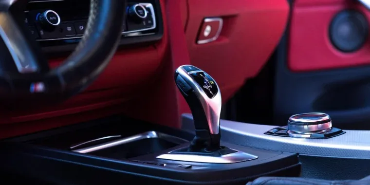 Close-up view of a modern car’s transmission gear shift lever and center console, featuring red and black interior accents—captured in Pocatello, Idaho.