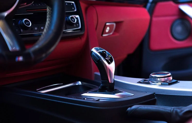 Close-up view of a modern car’s transmission gear shift lever and center console, featuring red and black interior accents—captured in Pocatello, Idaho.