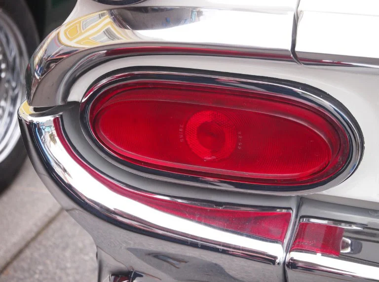 Close-up of a classic car’s red tail light with chrome trim, showing reflections and part of the vehicle body—perfectly capturing the attention to detail found at top brake service shops in Colorado Springs.